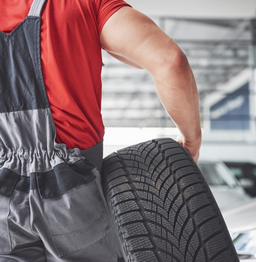 Mechanic holding a tire tire at the repair garage. replacement of winter and summer tires Mechanic holding a tire tire at the repair garage. replacement of winter and summer tires.